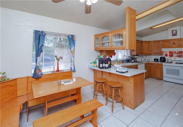 13182 Third St, Clearlake Oaks, CA 95423 - kitchen featuring white appliances, vaulted ceiling, under cabinet range hood, a peninsula, and glass insert cabinets