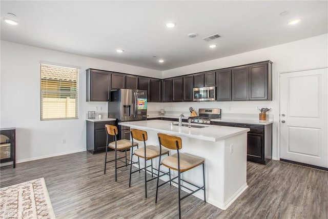 1737 Arcus Ct, Beaumont, CA 92223 - kitchen with appliances with stainless steel finishes, wood finished floors, a kitchen bar, light countertops, and dark brown cabinets