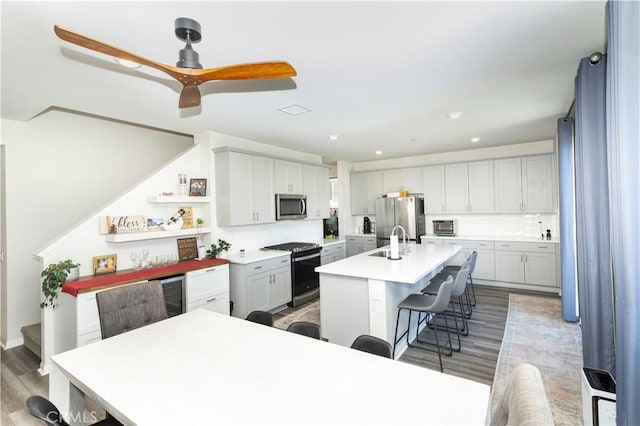 28252 Farm Creek Way, Valley Center, CA 92082 - kitchen featuring appliances with stainless steel finishes, a breakfast bar area, wood finished floors, a kitchen island with sink, and light countertops