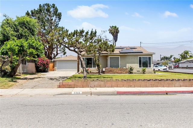 5342 Kingsley St, Montclair, CA 91763 - view of front of property featuring stucco siding, roof mounted solar panels, a front lawn, and a garage