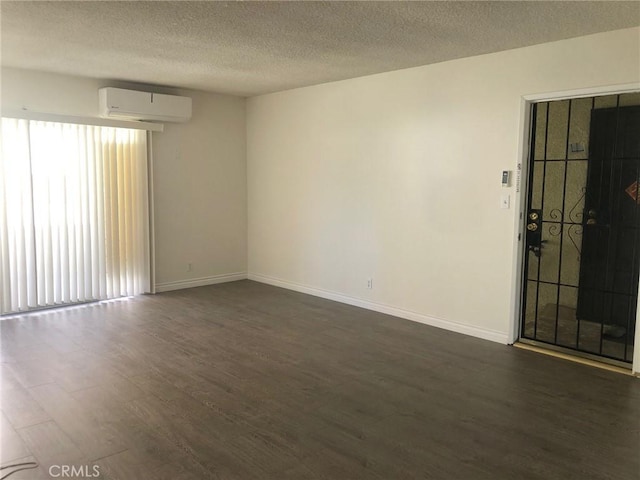 218 N Nicholson Ave, Monterey Park, CA 91755 - unfurnished room with an AC wall unit, dark wood-style floors, a textured ceiling, and baseboards