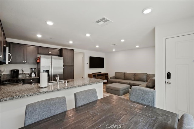 7155 Citrus Ave Unit 320, Fontana, CA 92336 - kitchen with a peninsula, dark brown cabinets, appliances with stainless steel finishes, light stone countertops, and recessed lighting