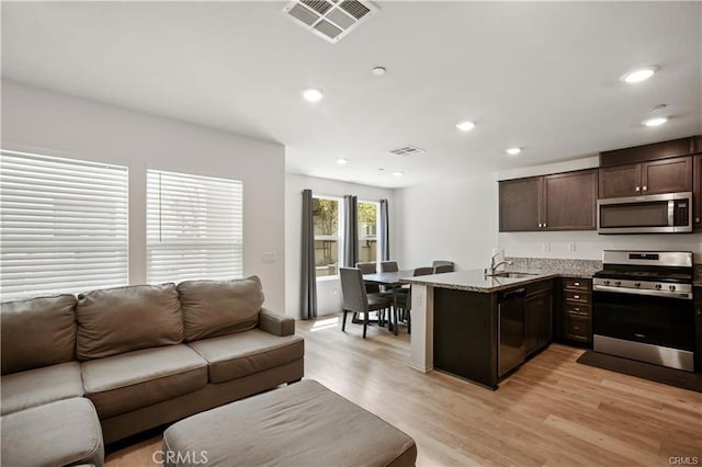 7155 Citrus Ave Unit 320, Fontana, CA 92336 - kitchen with stainless steel appliances, open floor plan, dark brown cabinets, a peninsula, and recessed lighting