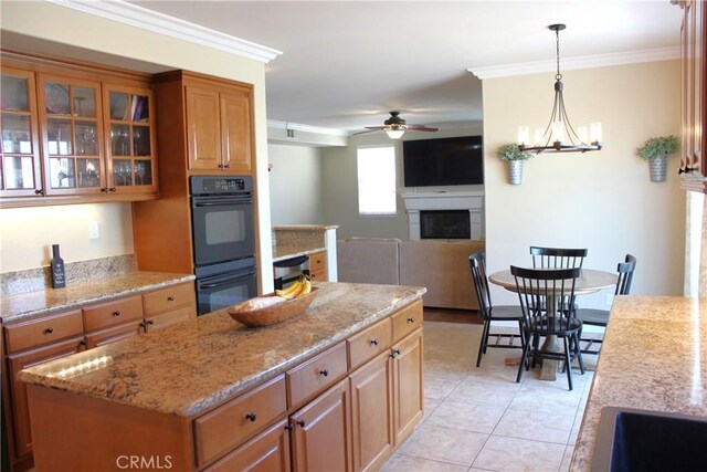 45344 Saint Tisbury St, Temecula, CA 92592 - kitchen with a fireplace, a ceiling fan, light stone counters, glass insert cabinets, and ornamental molding