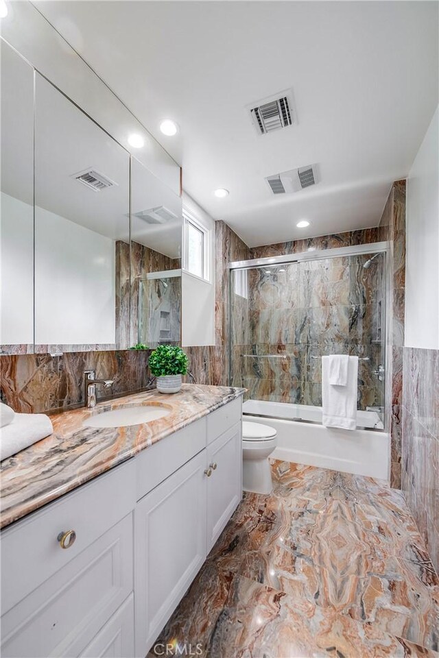 4820 Encino Ter, Encino, CA 91316 - full bathroom featuring toilet, bath / shower combo with glass door, vanity, marble finish flooring, and tile walls