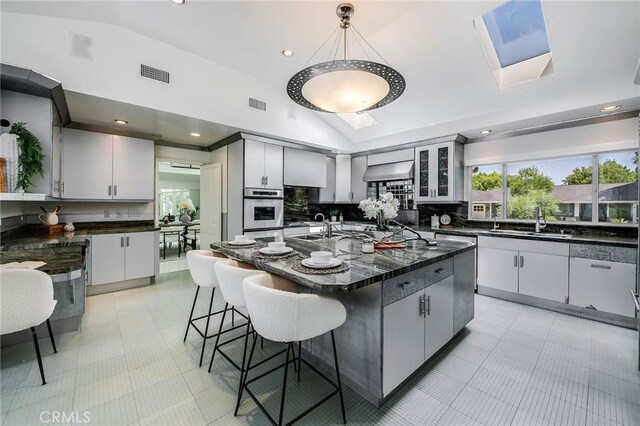 4820 Encino Ter, Encino, CA 91316 - kitchen featuring vaulted ceiling, a sink, backsplash, a breakfast bar, and pendant lighting