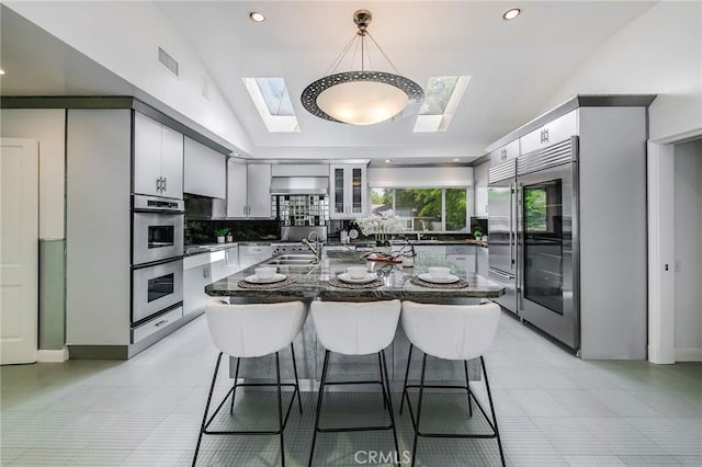 4820 Encino Ter, Encino, CA 91316 - kitchen featuring a skylight, appliances with stainless steel finishes, dark countertops, decorative backsplash, and lofted ceiling