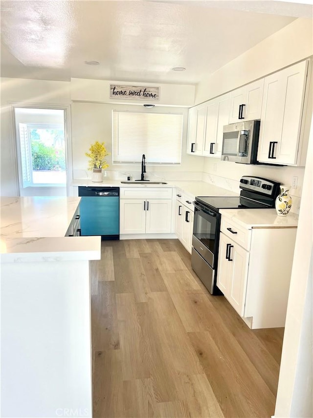 29041 Desert Hills Rd, Menifee, CA 92586 - kitchen featuring appliances with stainless steel finishes, white cabinetry, light countertops, and light wood-style floors