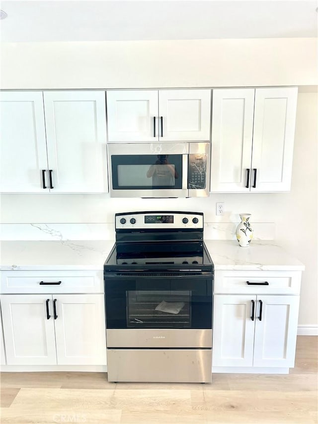 29041 Desert Hills Rd, Menifee, CA 92586 - kitchen featuring stainless steel appliances, white cabinets, light stone countertops, and light wood-style floors
