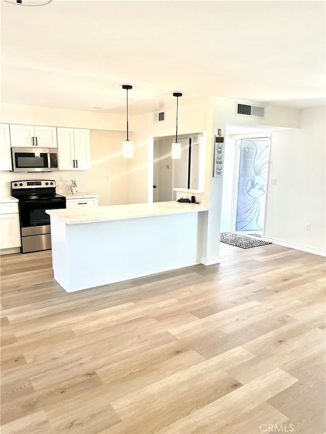 29041 Desert Hills Rd, Menifee, CA 92586 - kitchen featuring appliances with stainless steel finishes, light wood-style floors, light countertops, white cabinets, and decorative light fixtures