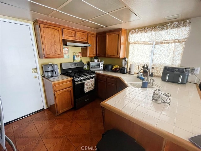 1186 Runaway Cir, Colton, CA 92324 - kitchen with stainless steel gas range oven, under cabinet range hood, tile counters, a sink, and brown cabinets