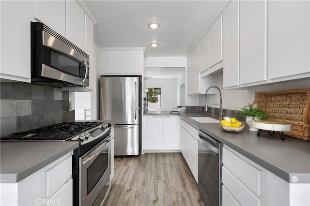 190 N Singingwood St Unit 1, Orange, CA 92869 - kitchen featuring appliances with stainless steel finishes, decorative backsplash, light wood finished floors, white cabinets, and recessed lighting