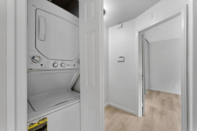 12590 Carmel Creek Rd Unit 1, San Diego, CA 92130 - laundry room with stacked washing machine and dryer, light wood-style floors, and baseboards