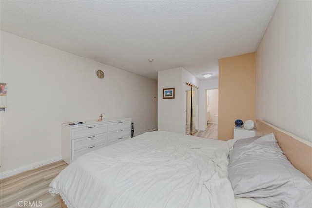 22224 S Vermont Ave Unit 102C, Torrance, CA 90502 - bedroom with light wood finished floors, connected bathroom, and a textured ceiling