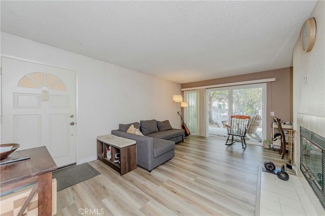 22224 S Vermont Ave Unit 102C, Torrance, CA 90502 - living room featuring light wood finished floors, a textured ceiling, and a tile fireplace