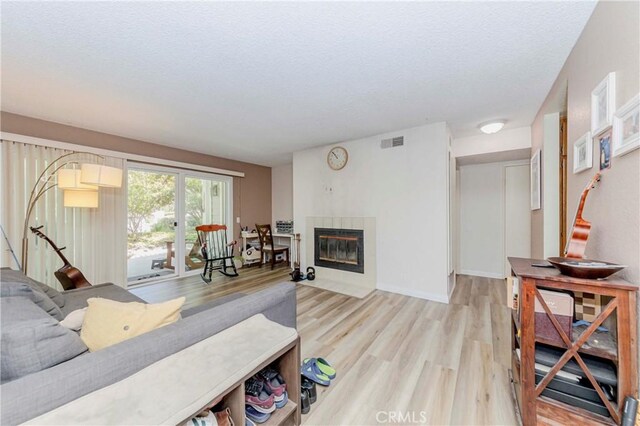 22224 S Vermont Ave Unit 102C, Torrance, CA 90502 - living room featuring a textured ceiling, light wood-style flooring, and a fireplace