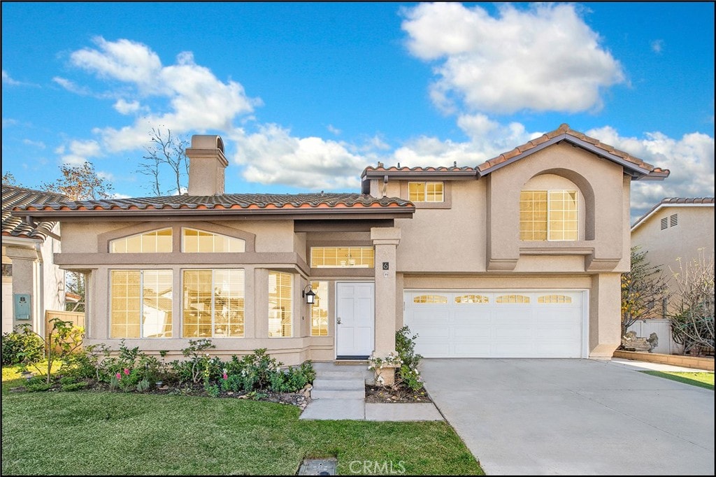 6 Firecrest Ln, Aliso Viejo, CA 92656 - mediterranean / spanish house with stucco siding, concrete driveway, a tiled roof, an attached garage, and a chimney