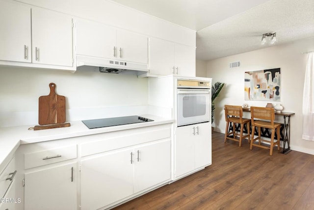 815 Perry Ave, Montebello, CA 90640 - kitchen featuring white oven, under cabinet range hood, black electric cooktop, dark wood finished floors, and white cabinets