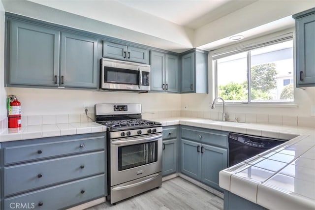11112 Camellia Ave, Fountain Valley, CA 92708 - kitchen with appliances with stainless steel finishes, a sink, light wood-style floors, and tile countertops
