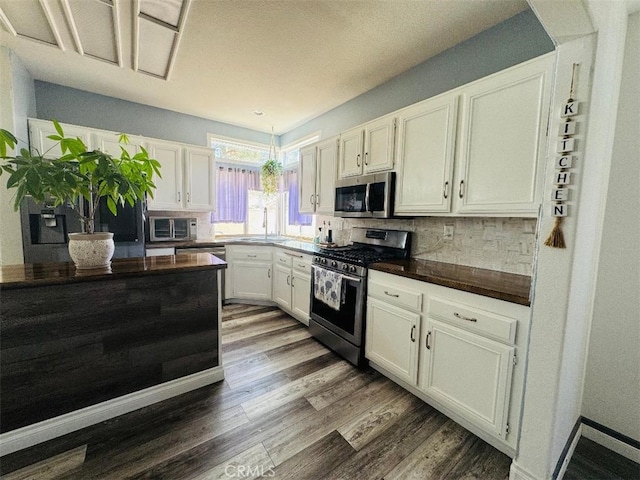 12477 Redrock Ct, Victorville, CA 92392 - kitchen featuring stainless steel appliances, a sink, dark wood-type flooring, white cabinetry, and decorative backsplash