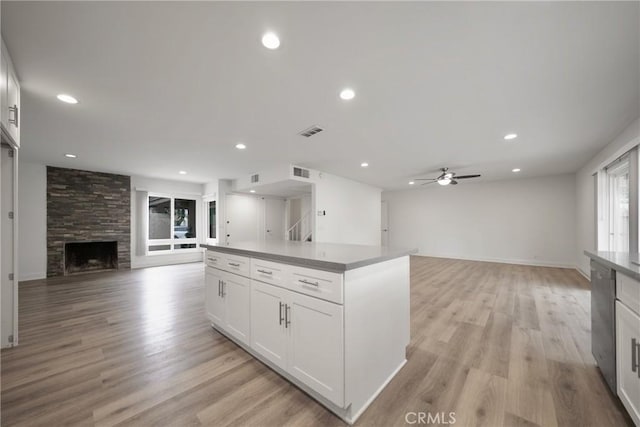 8190 Crowley Cir, Buena Park, CA 90621 - kitchen featuring open floor plan, a fireplace, white cabinets, a ceiling fan, and light wood finished floors