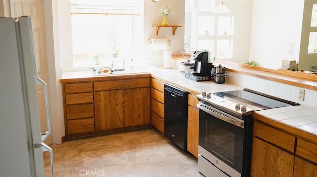 32455 Scandia Dr, Running Springs, CA 92382 - kitchen with dishwasher, stainless steel electric stove, freestanding refrigerator, tile counters, and brown cabinetry