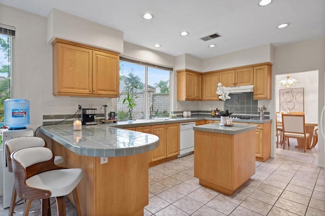 12032 Caneridge Rd, San Diego, CA 92128 - kitchen featuring white dishwasher, tile countertops, under cabinet range hood, a peninsula, and decorative backsplash