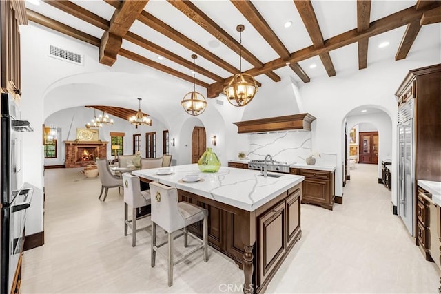 20 Cactus, Irvine, CA 92603 - kitchen with a chandelier, arched walkways, a breakfast bar area, beamed ceiling, and light stone countertops