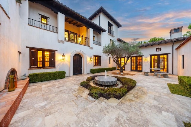 20 Cactus, Irvine, CA 92603 - back of house at dusk featuring french doors, stucco siding, and a balcony