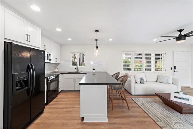 2175 S Coast Hwy Unit 16, Laguna Beach, CA 92651 - kitchen with black appliances, open floor plan, dark countertops, a kitchen bar, and a peninsula