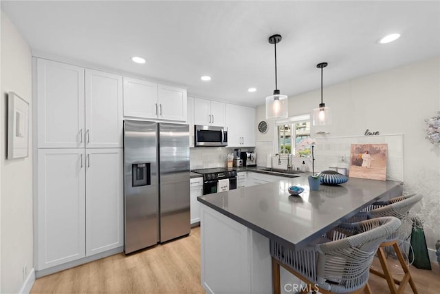 2175 S Coast Hwy Unit 16, Laguna Beach, CA 92651 - kitchen with appliances with stainless steel finishes, a peninsula, light wood-type flooring, white cabinetry, and dark countertops
