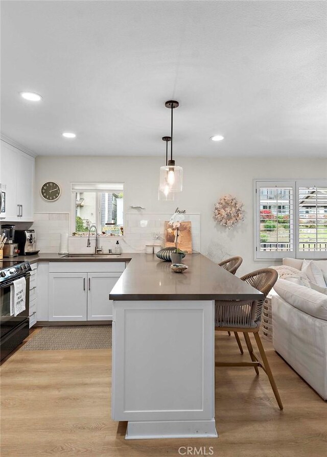 2175 S Coast Hwy Unit 16, Laguna Beach, CA 92651 - kitchen featuring black / electric stove, light wood-style flooring, decorative backsplash, dark countertops, and recessed lighting