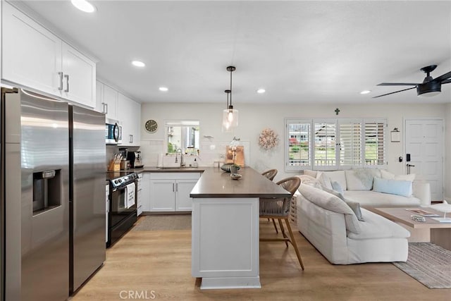 2175 S Coast Hwy Unit 16, Laguna Beach, CA 92651 - kitchen featuring appliances with stainless steel finishes, open floor plan, a peninsula, a breakfast bar, and white cabinets