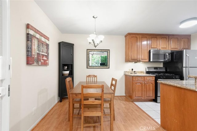 4727 W 147th St Unit 225, Lawndale, CA 90260 - kitchen featuring stainless steel appliances, light wood-style floors, a chandelier, light stone countertops, and brown cabinets