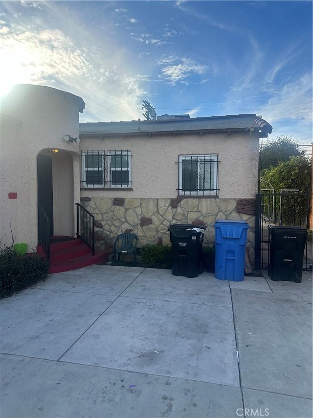 8943 S Hobart Blvd, Los Angeles, CA 90047 - rear view of property featuring stucco siding, stone siding, and a patio area