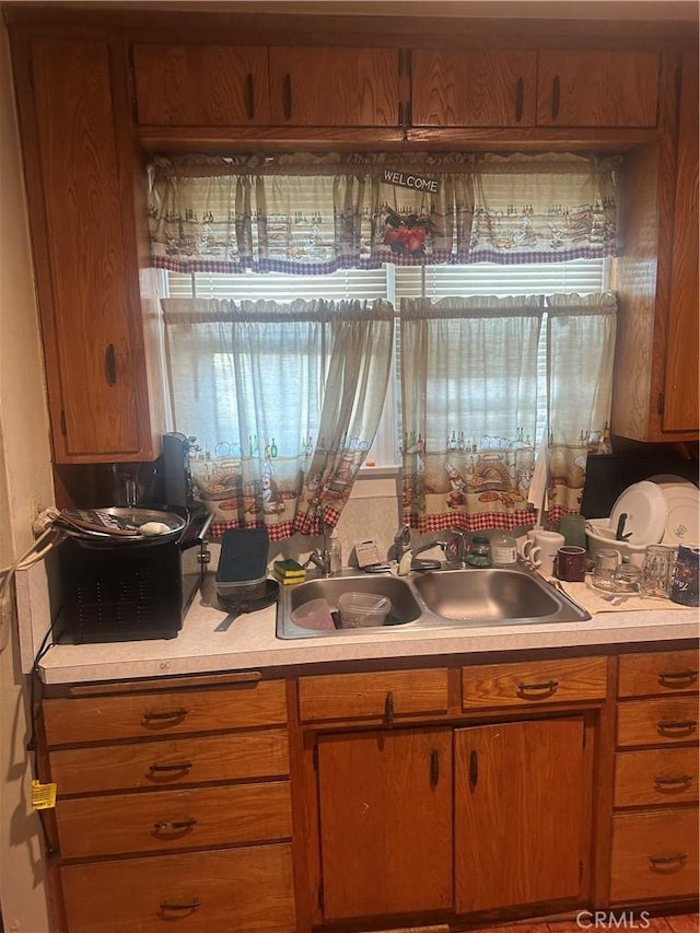 8943 S Hobart Blvd, Los Angeles, CA 90047 - kitchen with a sink, light countertops, and brown cabinetry