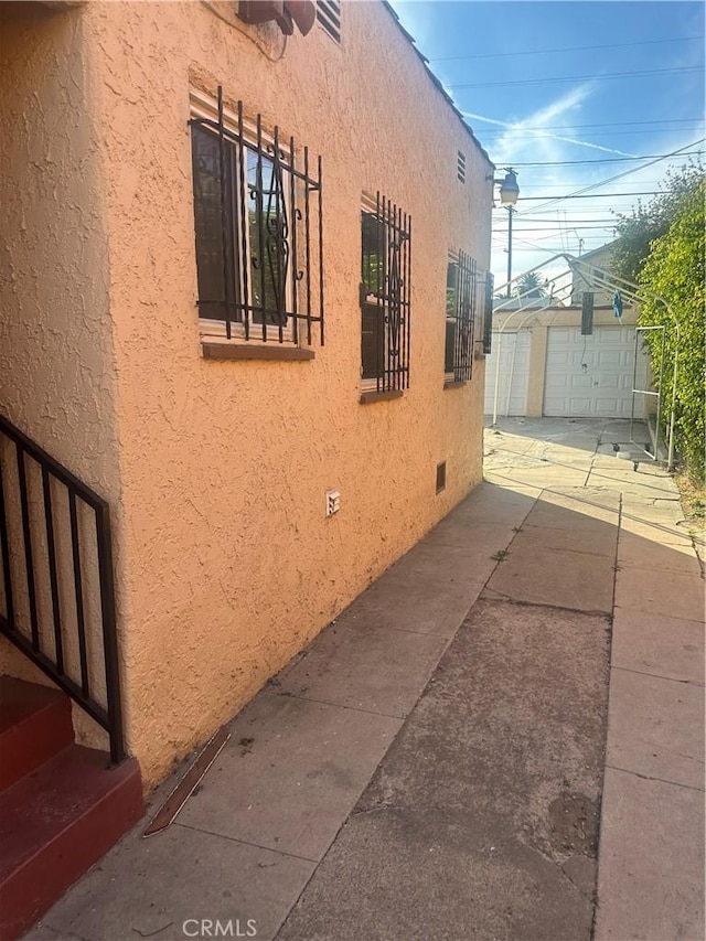 8943 S Hobart Blvd, Los Angeles, CA 90047 - view of property exterior featuring stucco siding, an outdoor structure, and driveway