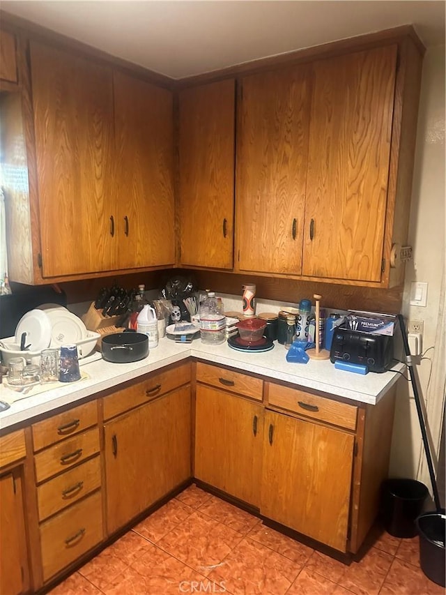 8943 S Hobart Blvd, Los Angeles, CA 90047 - kitchen featuring light countertops, brown cabinets, and light tile patterned flooring