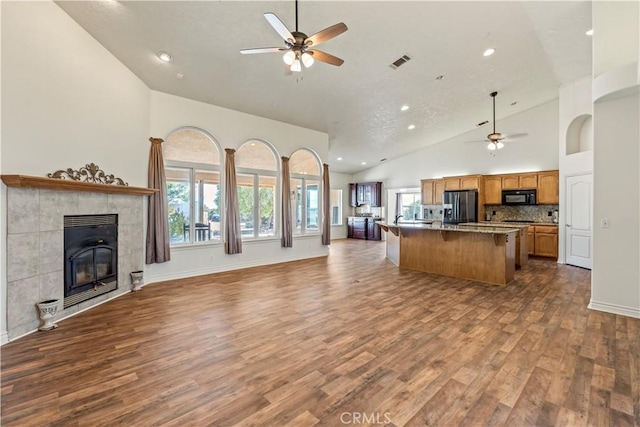 9098 Rattlesnake Rd, Phelan, CA 92371 - kitchen featuring stainless steel fridge, open floor plan, black microwave, ceiling fan, and high vaulted ceiling
