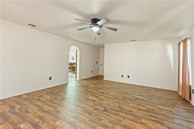 9098 Rattlesnake Rd, Phelan, CA 92371 - spare room featuring ceiling fan, arched walkways, wood finished floors, and baseboards
