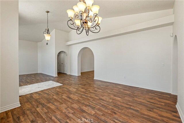 9098 Rattlesnake Rd, Phelan, CA 92371 - spare room with arched walkways, vaulted ceiling, wood finished floors, baseboards, and a chandelier
