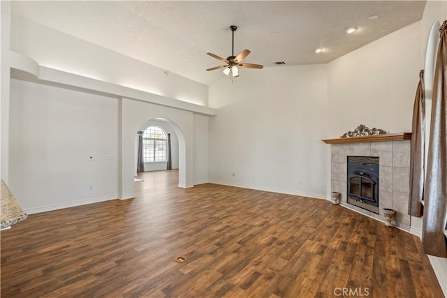 9098 Rattlesnake Rd, Phelan, CA 92371 - unfurnished living room featuring a ceiling fan, a tiled fireplace, wood finished floors, and arched walkways