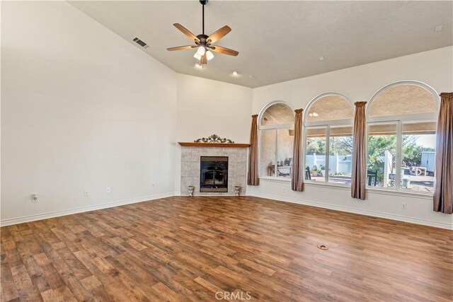 9098 Rattlesnake Rd, Phelan, CA 92371 - unfurnished living room featuring lofted ceiling, wood finished floors, a ceiling fan, baseboards, and a tile fireplace