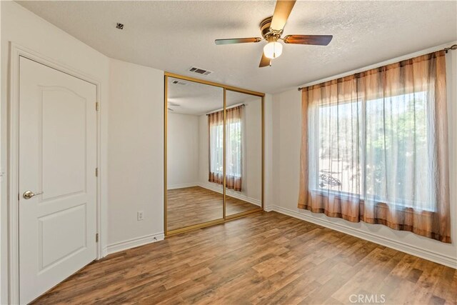 9098 Rattlesnake Rd, Phelan, CA 92371 - unfurnished bedroom featuring wood finished floors, a textured ceiling, a closet, baseboards, and a ceiling fan