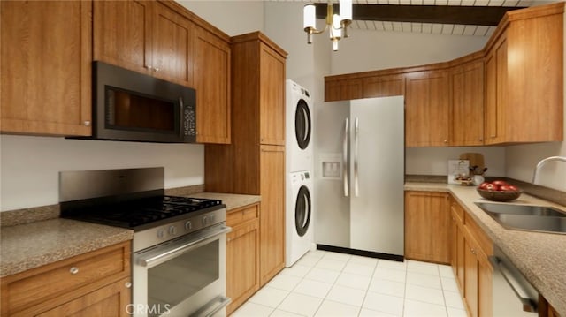 445 Longfellow Ave, Hermosa Beach, CA 90254 - kitchen featuring appliances with stainless steel finishes, stacked washing machine and dryer, vaulted ceiling, brown cabinetry, and light tile patterned flooring