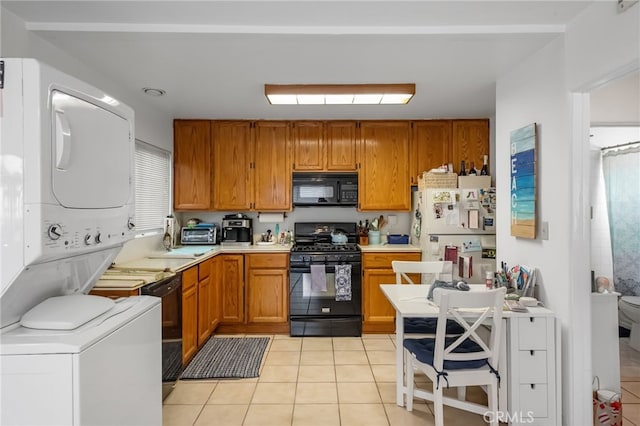 445 Longfellow Ave, Hermosa Beach, CA 90254 - kitchen with black appliances, estacked washer and dryer, light tile patterned floors, light countertops, and brown cabinets
