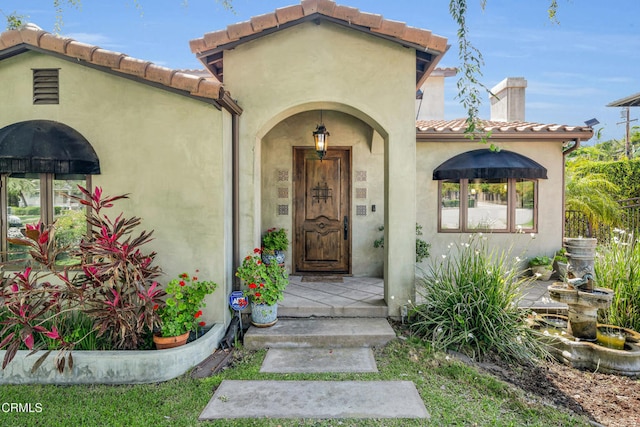 171 N Sunset Pl, Monrovia, CA 91016 - view of exterior entry with a tile roof, a chimney, and stucco siding