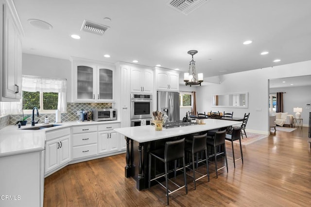 171 N Sunset Pl, Monrovia, CA 91016 - kitchen featuring appliances with stainless steel finishes, white cabinetry, a kitchen bar, dark wood-style flooring, and backsplash