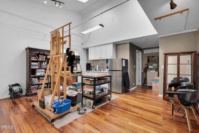 171 N Sunset Pl, Monrovia, CA 91016 - kitchen with freestanding refrigerator, an AC wall unit, light wood-style flooring, rail lighting, and a towering ceiling
