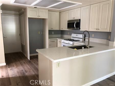 3249 Cambridge Dr, Chino Hills, CA 91709 - kitchen featuring stainless steel microwave, white range with gas cooktop, a peninsula, a sink, and dark wood finished floors
